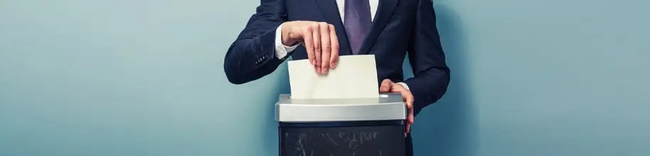 a man in blue suit and purple tie shredding a paper with a shredding machine